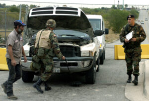 soldiers inspect under cars with mirrors