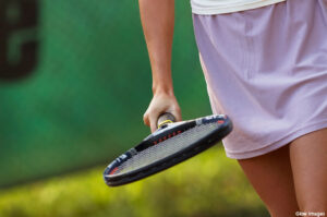 Mid section view of a young woman hitting a tennis ball with a tennis racket