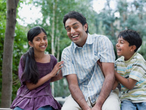 Waist-length view of a South Asian girl and boy tickling their father. Photo: © Image Source, all rights reserved.