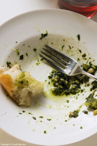 Above view of the remains of pesto and white bread on a plate with a fork. Copyright © FoodCollection. MHE World.