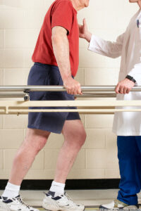 profile view of a senior man using parallel bars to help him walk