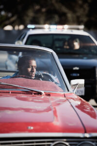 African man in convertible being pulled over by police. 