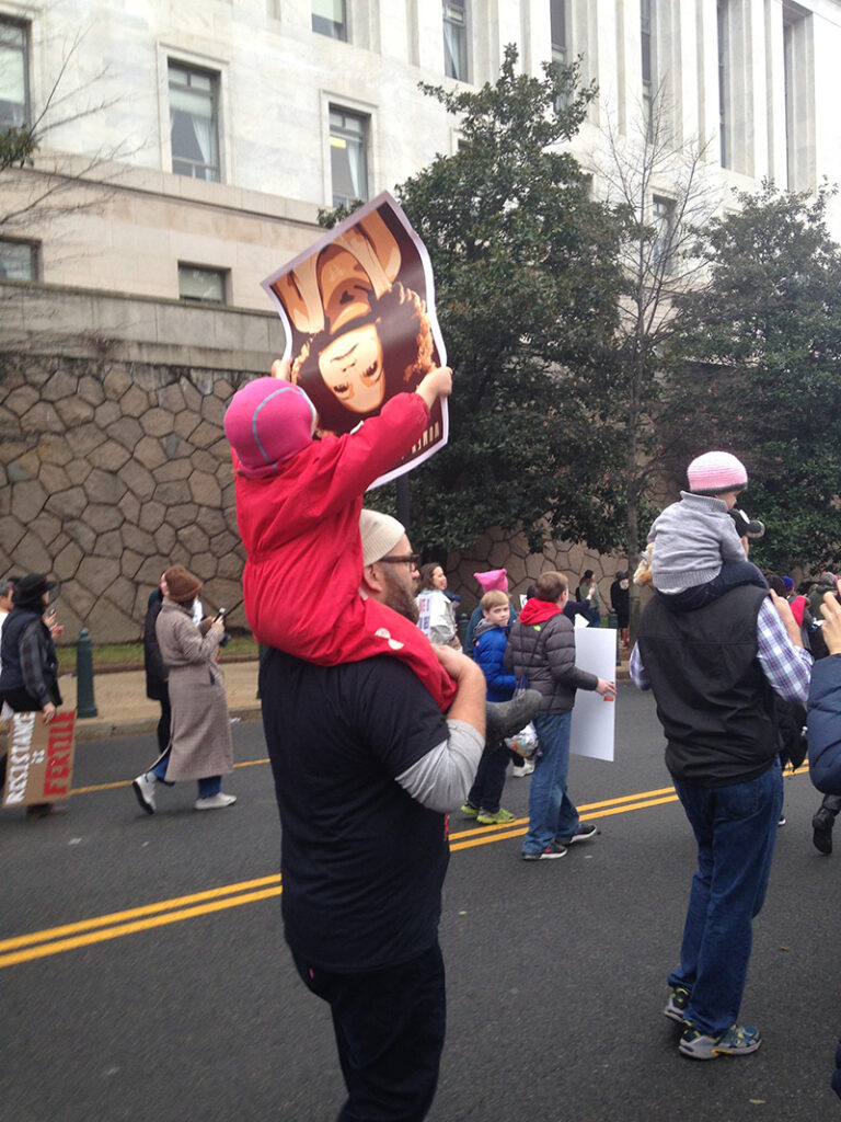 kid on dad's shoulder, marching