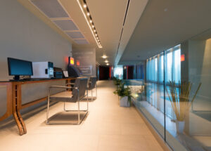 Long shot view of a line of empty desks with computers in an open plan, contemporary office building,