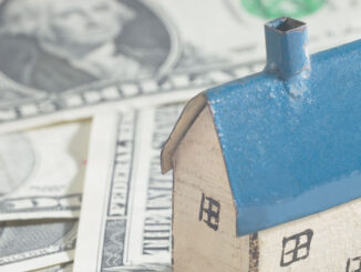 Close-up of a small house on a surface of US paper currency