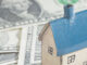 Close-up of a small house on a surface of US paper currency