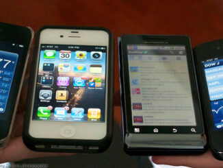 High-angle close-up view four smartphones displayed in a row across the palms of two human hands