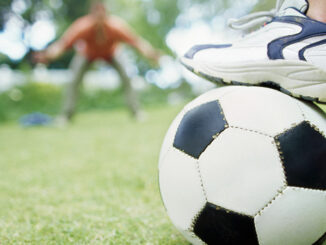 Father and son playing soccer in garden (10-11)