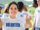 happy volunteer girl showing thumbs up sign group in background
