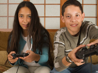 Children sitting on sofa playing video games