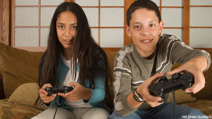 102314_01P_FS Children sitting on sofa playing video games