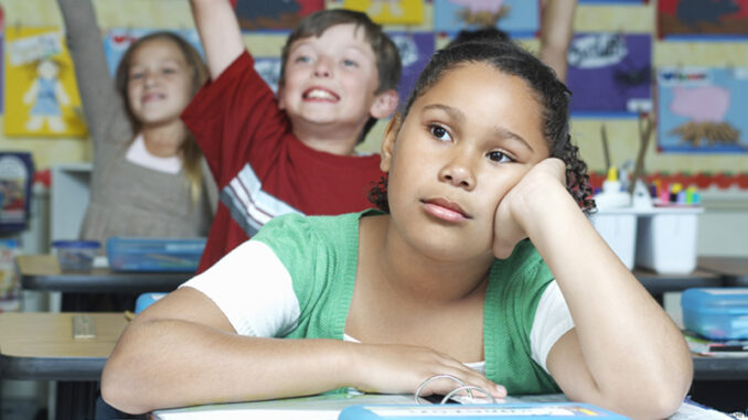 120414_01P_FS Three pupils in classroom, two with raised hands, one pensive. Photo: moodboard/Getty Images