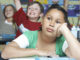 Three pupils in classroom, two with raised hands, one pensive. Photo: moodboard/Getty Images