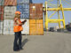 Worker with clipboard in cargo container terminal. Photo: Chris Sattlberger/Blend Images LLC