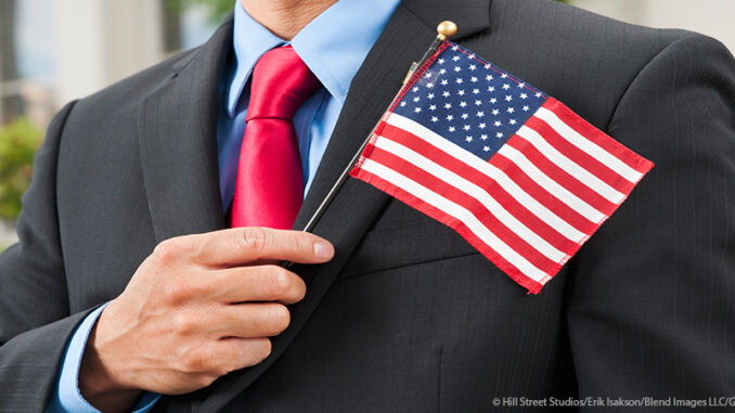030315_01P_FS Man in a business suit holding a small American flag against his chest