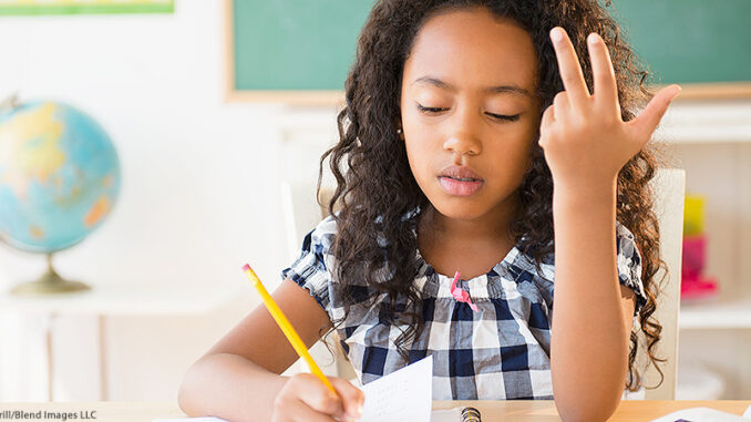 BLD124989 Head-and-shoulders view of a mixed-race girl counting on her fingers and writing in a notebook in class. ©JGI/Jamie Grill/Blend Images LLC. MHE World.