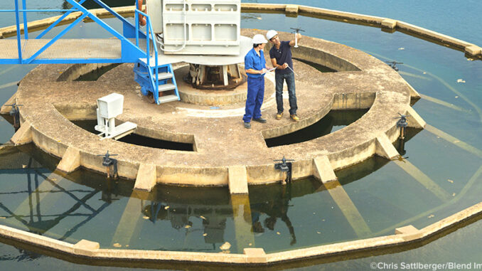 BLD119675-F High angle full-length view of two Hispanic men standing on a platform and checking the water quality in a sewage treatment plant. ©Chris Sattlberger/Blend Images LLC. MHE World.