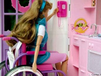 This was one of three images, (PHIL# 9135 - 9137), depicting an attempt by a toy manufacturer to produce a toy character which displayed characteristics that emulated those of a mobility-challenged person who was a wheelchair user. This disabled character was portrayed in the manner that echoed the style of the rest of their toy line. In doing so, the manufacturer tried to, in a sense, mainstream the knowledge of what is faced by the disabled in the real world through play, and therefore, was as educational, as it was entertaining to the childhood end user demographic group. PHIL image 9137, showed Ron Mace looking through a door in the playhouse. © Center for Universal Design/CDC. MHE World.