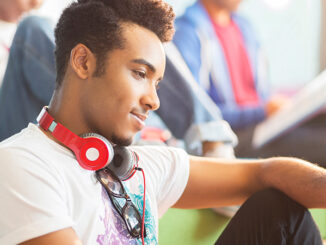 University student using digital tablet in lounge. Robert Daly/Glow Images. MHE World.