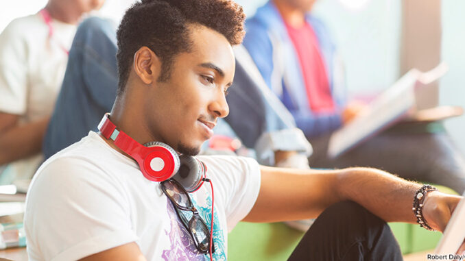 412-13713 University student using digital tablet in lounge. Robert Daly/Glow Images. MHE World.