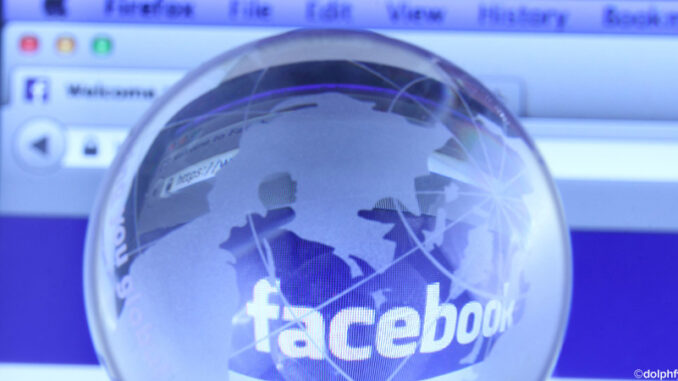 052516_02P_FS Selective focus close-up view of a small, transparent glass globe of the earth placed in front of a computer monitor displaying Facebook. The globe creates a fisheye magnification of the word 'facebook' on the screen. As of today, Facebook is the largest social media network on the web. ©dolphfyn / Alamy. MHE World