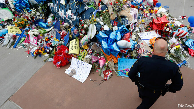 071216_02P_FS A policeman visits a makeshift memorial at the Dallas police headquarters, Monday, July 11, 2016, in Dallas. Five police officers were killed and several injured during a shooting in downtown Dallas last Thursday night. Eric Gay/AP Images. http://www.apimages.com/metadata/Index/APTOPIX-Police-Shootings-Dallas/2b62b93227e943d4b1bc1fbfe5886b30/1/0