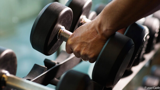07261602P_FS Close-up of a man's hands lifting dumbbells from a gym rack. Fuse/Getty Images. MHE Canada;MHE USA.