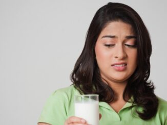 teenage female looking with slight disgust at a full glass of milk