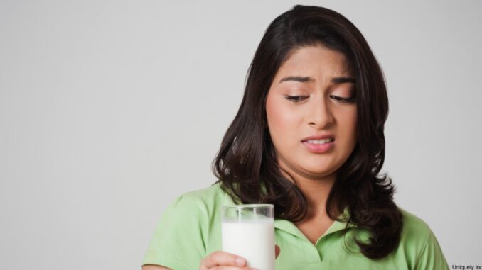 172596784 teenage female looking with slight disgust at a full glass of milk