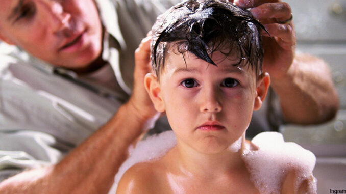 103116_02P_FS Head-and-shoulders view of a young boy in the bathtub, looking at the camera with a worried expression as his concerned father tries to wash his hair.