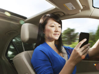 Seated view of a young Asian woman texting while driving inside her car. Credit: Michael Krinke/Getty Images