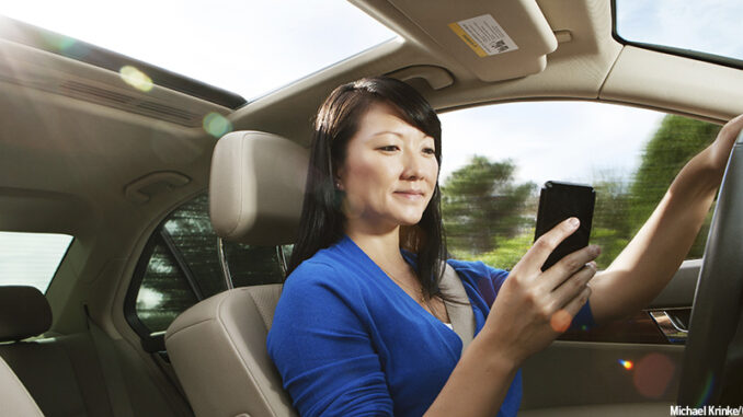 11117_03P_FS Seated view of a young Asian woman texting while driving inside her car. Credit: Michael Krinke/Getty Images