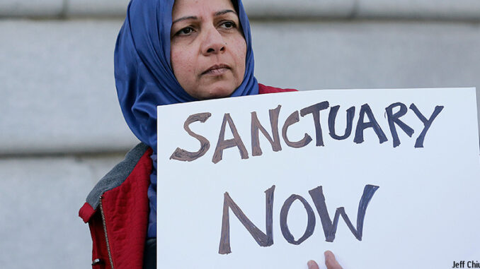 22817_02P_FS Moina Shaiq holds a sign at a rally outside of City Hall in San Francisco, Wednesday, Jan. 25, 2017. President Donald Trump moved aggressively to tighten the nation's immigration controls Wednesday, signing executive actions to jumpstart construction of his promised U.S.-Mexico border wall and cut federal grants for immigrant-protecting "sanctuary cities." Credit: Jeff Chiu/AP Images