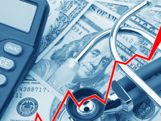 View of a rising red graph showing the high cost of health care atop USD bank notes, a stethoscope and calculator