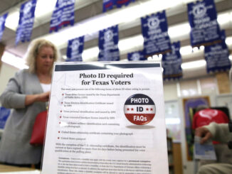 A sign explains voter ID requirements before participating in a primary election in Arlington, Texas.