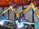 Three-quarter length view of a pair of metal inert gas welding robots at John Deere Harvester Works, East Moline, Illinois.