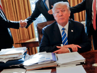 President Donald Trump sits at his desk after a meeting