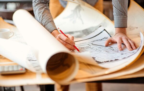 72417_01P_IS Selective-focus close-up view of an urban planner with a couple of layers of architectural drawings on a drafting table. Credit: RossHelen/Shutterstock.com