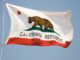 View of the California state flag flying in the breeze under a blue sky.