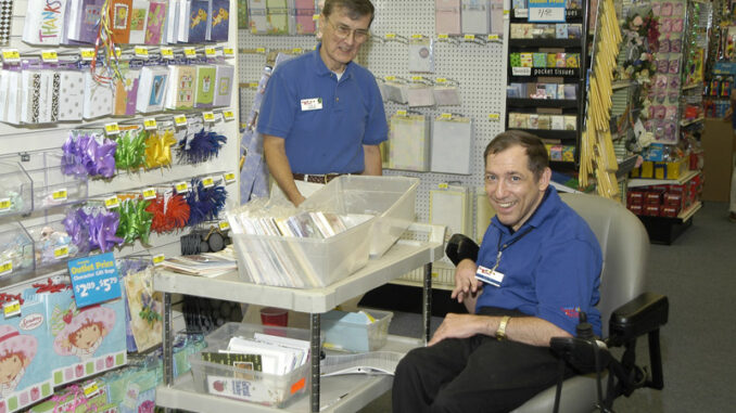 112717_01_IS Three-quarter-length view of a Caucasian man with a disability, utilizing a wheelchair for mobility and enjoying time with a coworker in a retail store.