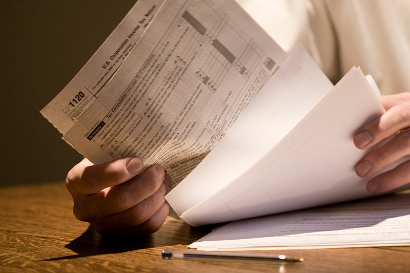 Close-up of man working on corporate income tax forms