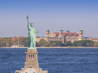 Digital composite of the Statue of Liberty junxtaposed with Ellis Island in the background.