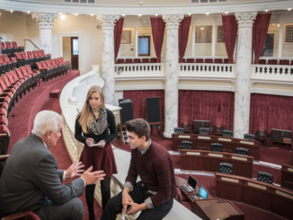 High-angle three-quarter-length view of two teenagers talking to a male politician in the senate gallery of the Idaho State Capitol building, Boise, Idaho
