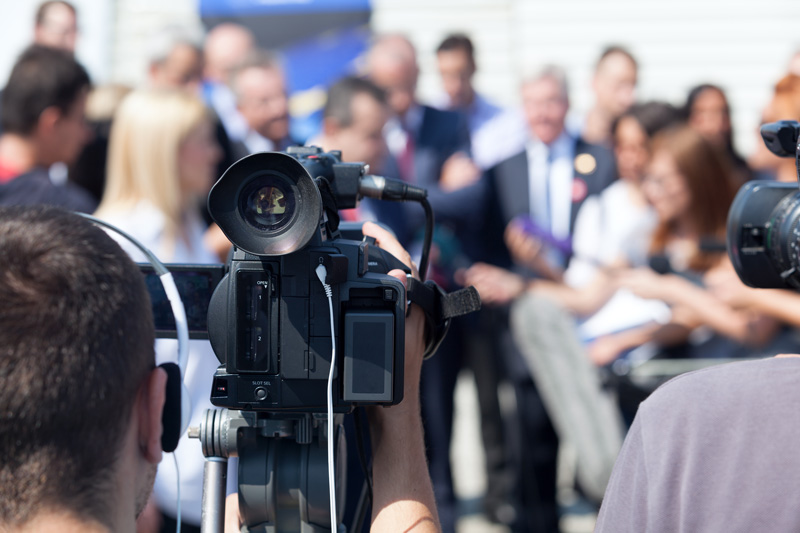 Filming an media event with a video camera. Press conference.