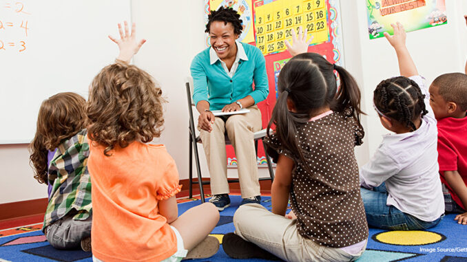 082018_01P_FS Teacher and children sitting on floors with hands raised