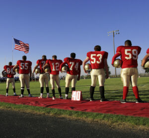 Football players standing at attention before the American flag