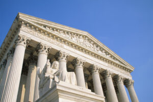 Low angle view of the Contemplation of Justice by James Earle Fraser and the west facade portico of the United States Supreme Court Building against a clear blue sky,