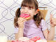 hungry little girl eat donuts