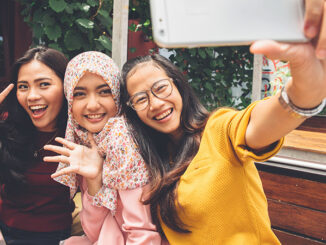 Portrait of happy young girl friend taking selfie together in cafe.