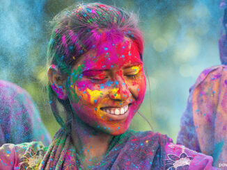 Young woman covered in colored dye enjoying Holi festival in Jaipur, India.